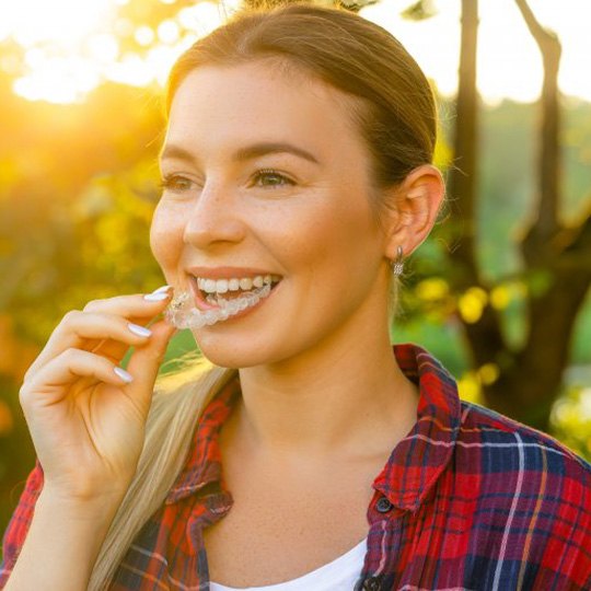 Woman living life while inserting her Invisalign at the park