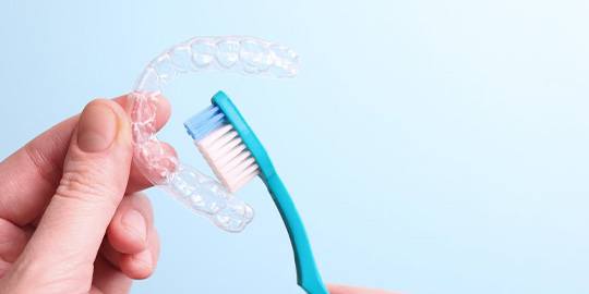 Close up of hand brushing Invisalign tray