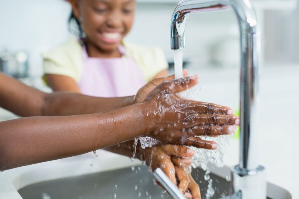 Two young people washing their hands.